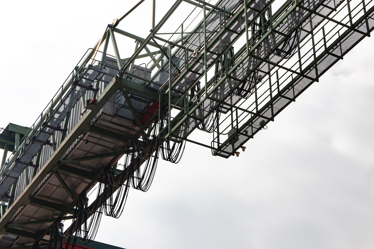 Close-up of an industrial metal structure with cables visible against a clear sky.